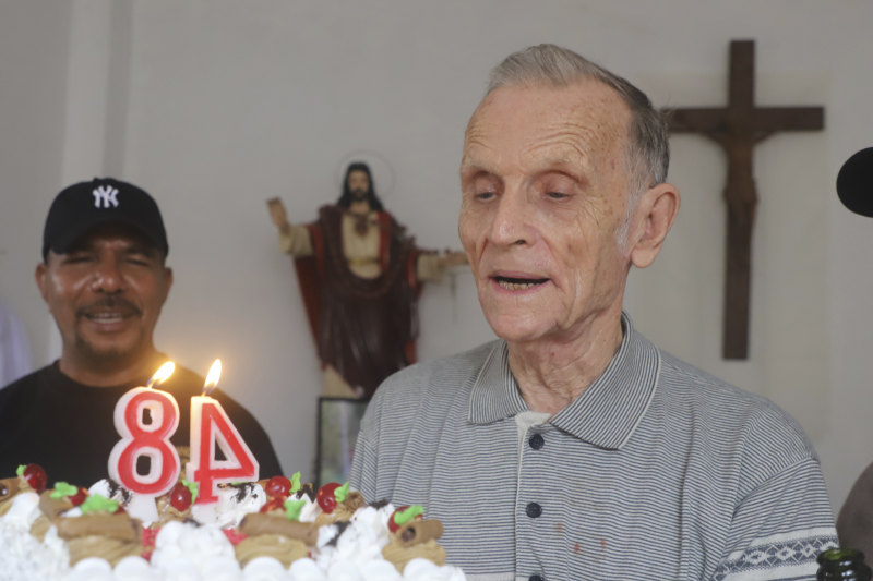 Now-defrocked Catholic priest Richard Daschbach, centre, is presented a cake during his 84th birthday in Dili in January. CREDIT:AP