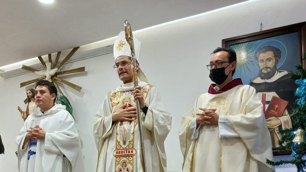 Jacinto and bishop Pérez Raygoza during a mass. A third cleric, wearing a facemask stands with them, 2023.